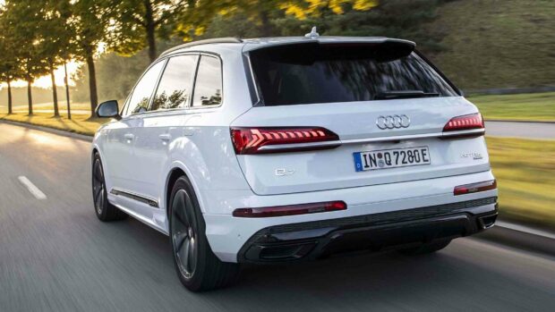 A white Audi Q7 is captured from the rear while driving along a road bordered by trees during daytime, 2K Desktop Wallpaper