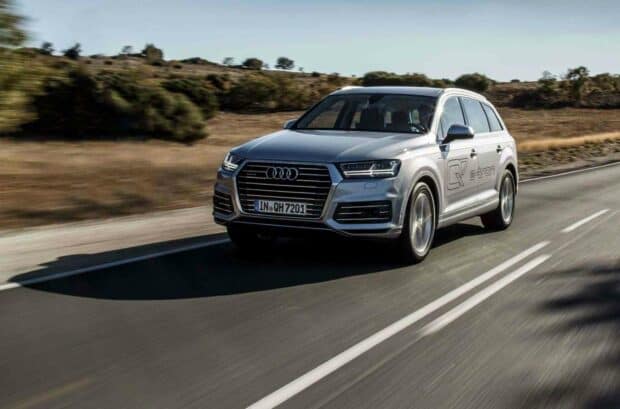 The Audi Q7 is driving swiftly on a clear rural road surrounded by trees and fields, HD Desktop Wallpaper