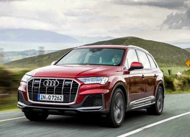 A red Audi Q7 is driving on a rural road with hills and cloudy sky in the background, HD Desktop Wallpaper