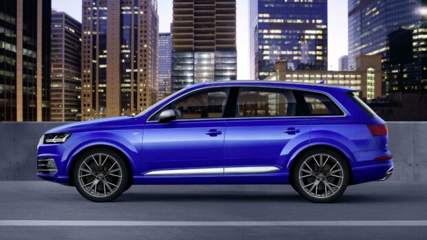 A blue Audi Q7 is parked in front of tall city skyscrapers at dusk, 4K Desktop Wallpaper