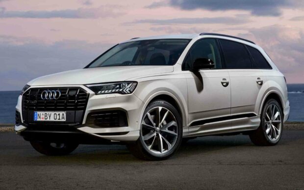 A white Audi Q7 is parked on a coastal road under a cloudy sky, featuring its sleek body and prominent grille, HD Desktop Wallpaper