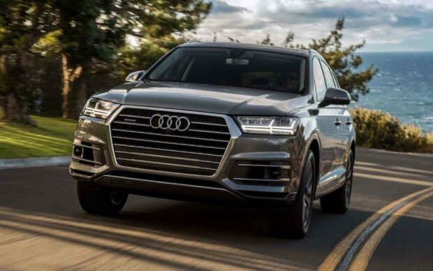 The Audi Q7 is driving smoothly along a coastal road with trees and ocean in the background, HD Desktop Wallpaper