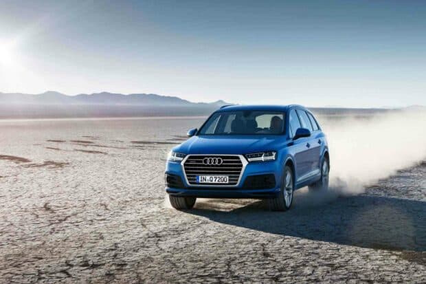 A blue Audi Q7 is driving swiftly across dry desert land with mountains in the background, HD Desktop Wallpaper