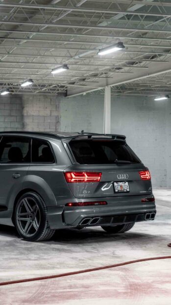 A gray Audi Q7 is parked inside a spacious garage with gray walls and lighting fixtures above, 2K Mobile Wallpaper