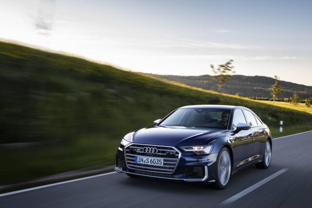 Audi S6 Driving On Scenic Road High Performance Luxury Sedan Wallpaper