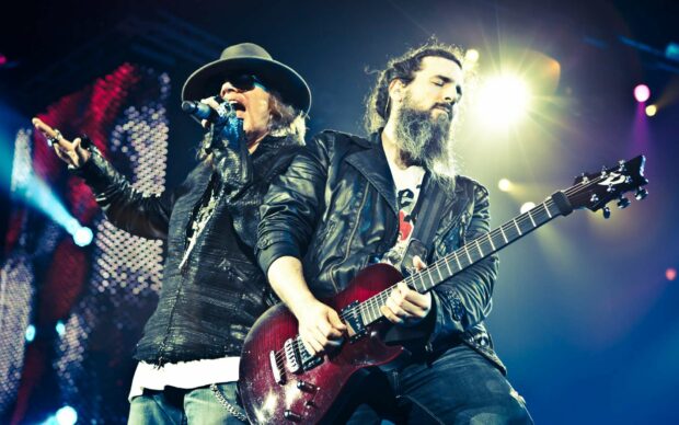 Axl Rose is singing passionately during a concert with a guitarist playing beside him, HD Desktop Wallpaper
