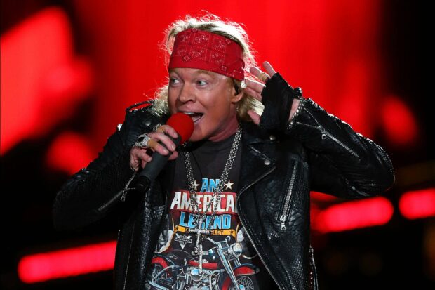 Axl Rose is singing passionately into a microphone during a concert, 2K Desktop Wallpaper