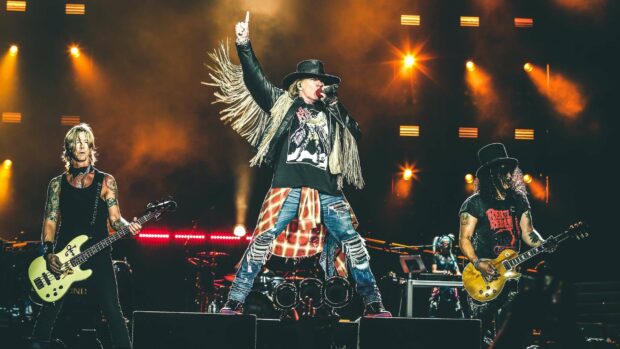 Axl Rose is singing passionately with the band during a concert, 2K Desktop Wallpaper