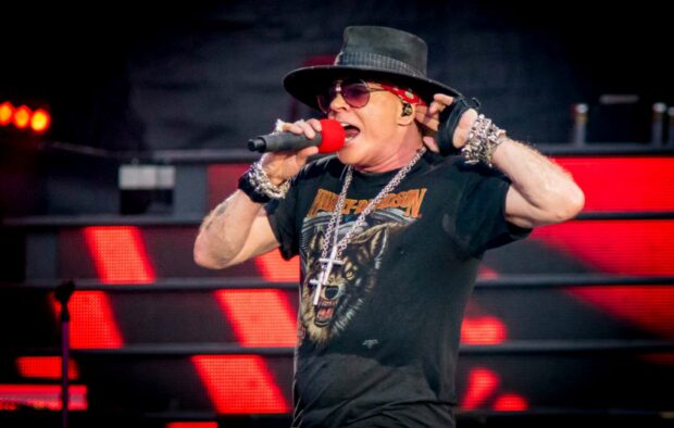 Axl Rose performing live with red microphone and black hat during a concert, HD Desktop Wallpaper