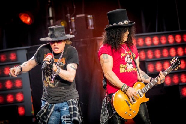 Axl Rose performing energetically with a guitarist playing an electric guitar during a concert, 2K Desktop Wallpaper