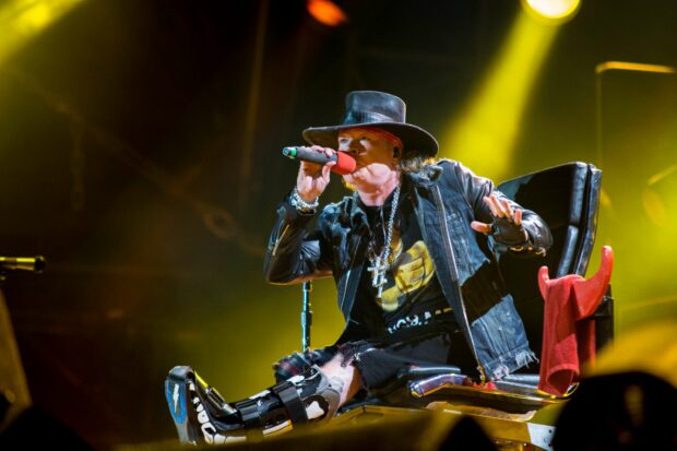 Axl Rose is singing in a leather jacket and hat during a live concert, 2K Desktop Wallpaper