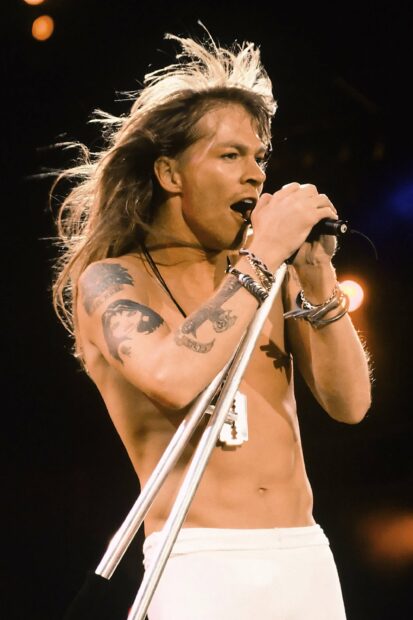 Axl Rose is performing passionately with a microphone on stage in this image, 2K Mobile Wallpaper