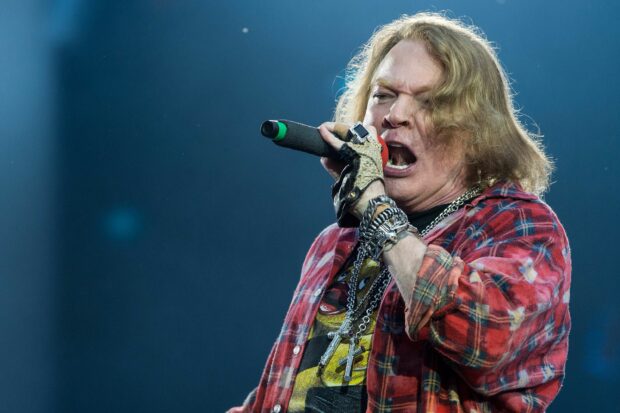 Axl Rose singing passionately during a live performance with a red plaid shirt, 2K Desktop Wallpaper