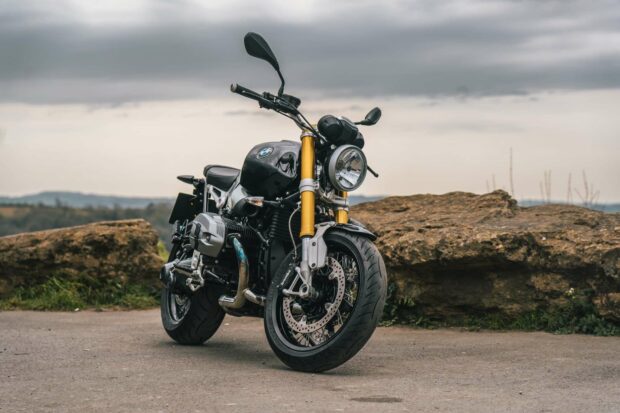 A BMW R Nine T motorcycle parked on a road near rocky terrain with an overcast sky, HD Desktop Wallpaper