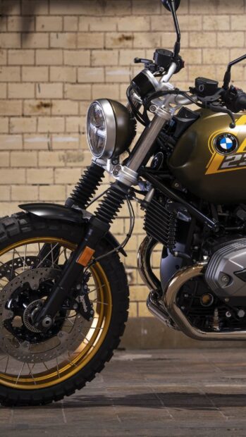 A close up view of the BMW R Nine T motorcycle front fork and gold wheel against a brick wall, 2K Mobile Wallpaper