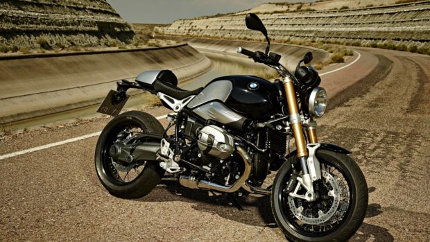 A BMW R Nine T motorcycle parked on a curved desert road near a concrete canal, 4K Desktop Wallpaper