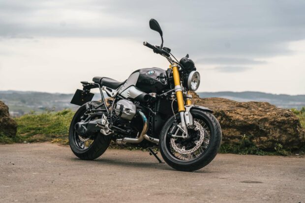 A black BMW R Nine T motorcycle parked on a rural road with rocks and hills in the background, HD Desktop Wallpaper