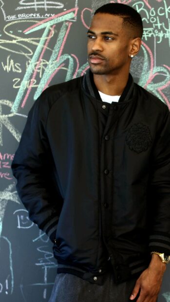 A man wearing a black jacket stands casually in front of a colorful chalkboard drawing showcasing Big Sean wallpapers, 4K Mobile Wallpaper
