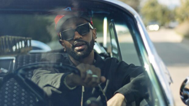 Big Sean is wearing sunglasses and a red cap while driving a car on a sunny day, HD Desktop Wallpaper