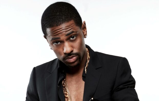 A close up of Big Sean wearing a black suit with gold chains against a white background, 2K Desktop Wallpaper