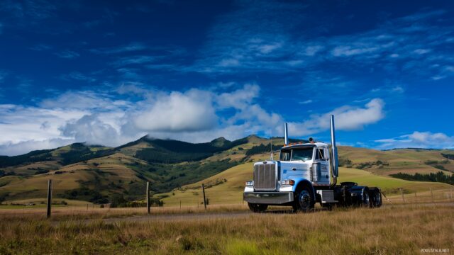 Big Truck HD Desktop Wallpaper, A Big Truck Parked In A Scenic Countryside Setting, Surrounded By Rolling Hills And Clear Blue Skies