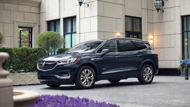 A black Buick Enclave SUV is parked on a stone driveway in front of a building with plants and lights, 4K Desktop Wallpaper