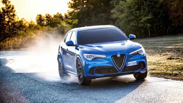 A blue Alfa Romeo car is driving through a wet and winding road surrounded by trees, 4K Desktop Wallpaper