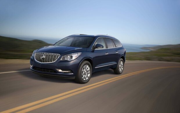 A blue Buick Enclave is driving along a winding coastal road with the ocean in the background, 2K Desktop Wallpaper