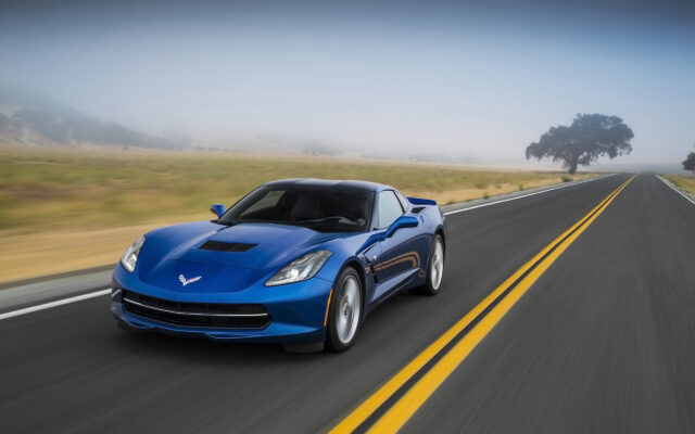Blue Chevrolet Corvette Driving On Open Road Stunning Wallpaper Background