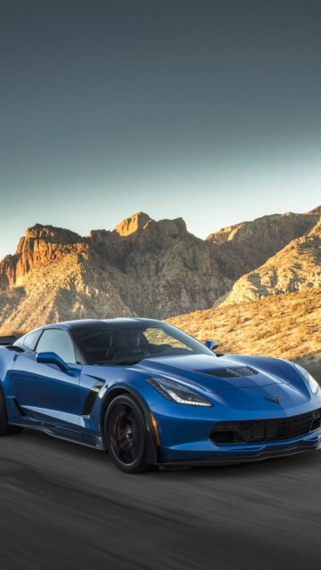 Blue Chevrolet Corvette Speeding On Desert Road With Rocky Mountains Background Wallpaper