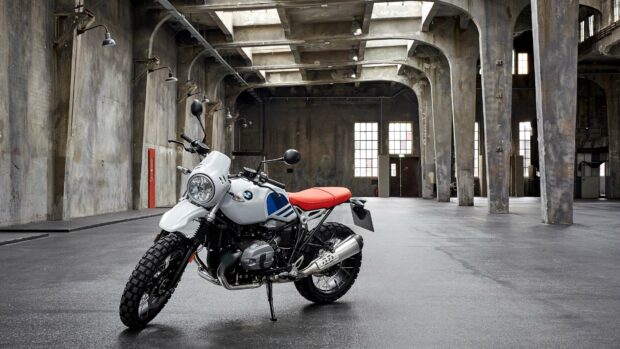 A Bmw R Nine T motorcycle with a red seat is parked inside an industrial warehouse with natural light, 4K Desktop Wallpaper