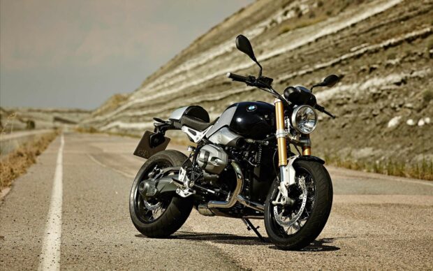 A Bmw R Nine T motorcycle is parked on a deserted road with rocky hills in the background, HD Desktop Wallpaper