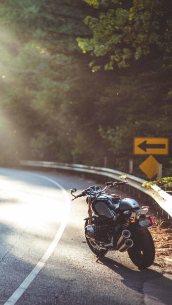 A BMW R Nine T motorcycle parked on a curved road surrounded by trees, 2K Mobile Wallpaper