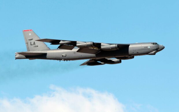 A Boeing B 52 is flying with extended wings against a clear blue sky, 2K Desktop Wallpaper
