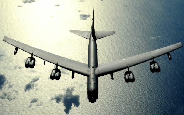 A Boeing B 52 aircraft soars above the ocean with sunlit water below, 2K Desktop Wallpaper