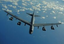 A Boeing B 52 is flying above the ocean with clouds scattered in the sky, 2K Desktop Wallpaper