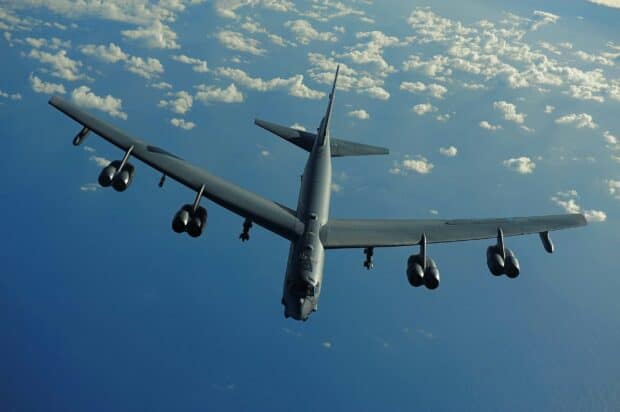A Boeing B 52 is flying above the ocean with clouds scattered in the sky, 2K Desktop Wallpaper
