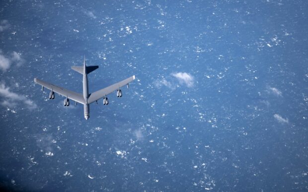 A Boeing B 52 is flying high above the ocean with clouds scattered below, 2K Desktop Wallpaper