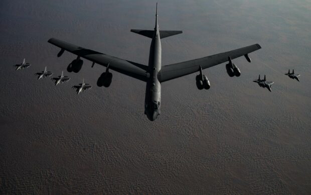 A Boeing B 52 is flying in formation with multiple fighter jets over a desert landscape, 2K Desktop Wallpaper