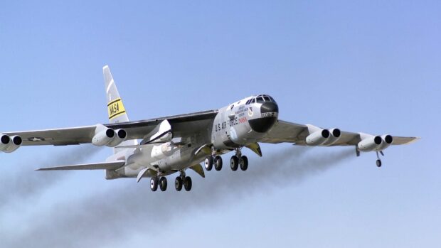 A Boeing B 52 aircraft is flying with landing gears down and smoke trailing from the engines, 2K Desktop Wallpaper