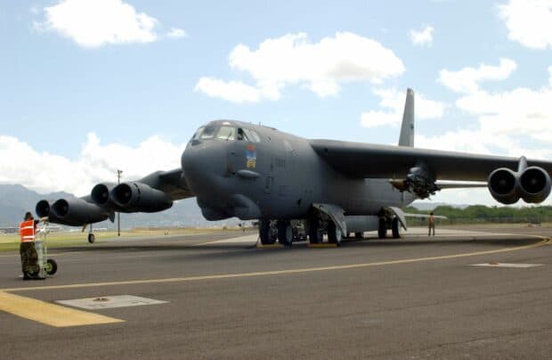 A Boeing B 52 strategic bomber is parked on a runway with crew members nearby, 2K Desktop Wallpaper