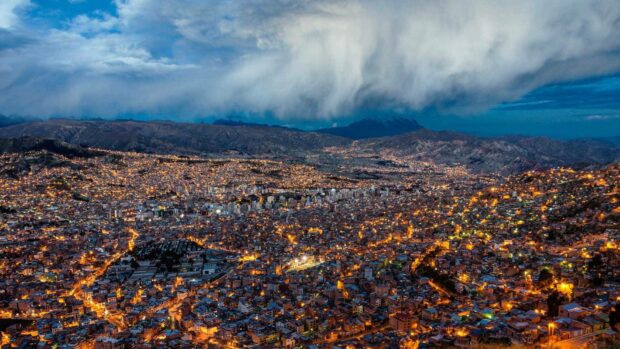 The Bolivia Wallpapers city is illuminated with golden lights under a cloudy sky in the evening, HD Desktop Wallpaper