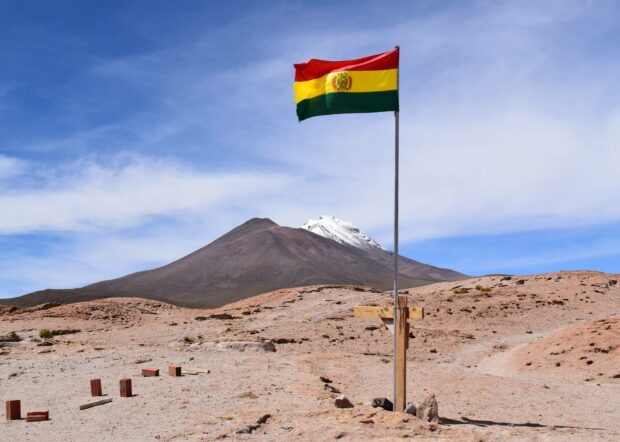 The Bolivian flag waves in the desert with mountains in the background, HD Desktop Wallpaper