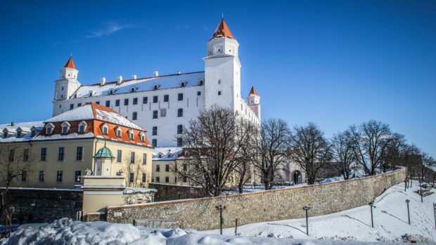 Bratislava wallpapers display the historic castle covered in snow under a clear blue sky, 4K Desktop Wallpaper