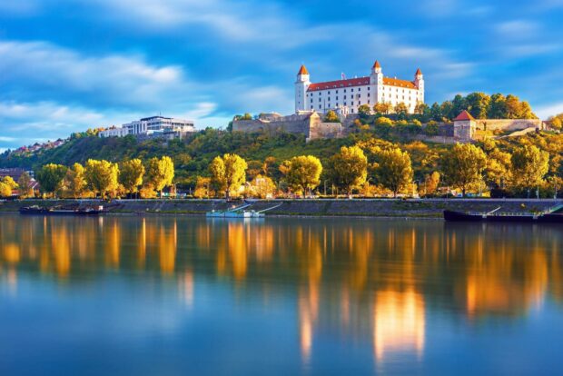 A stunning view of Bratislava with the castle and autumn trees reflecting on the river, HD Desktop Wallpaper
