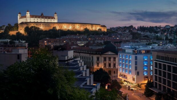 The Bratislava cityscape shows illuminated buildings and the historic castle during twilight, HD Desktop Wallpaper
