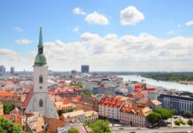 A panoramic view of Bratislava showing the old town, river, and city buildings under a cloudy sky, 2K Desktop Wallpaper