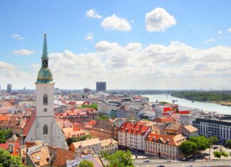 A panoramic view of Bratislava showing the old town, river, and city buildings under a cloudy sky, 2K Desktop Wallpaper