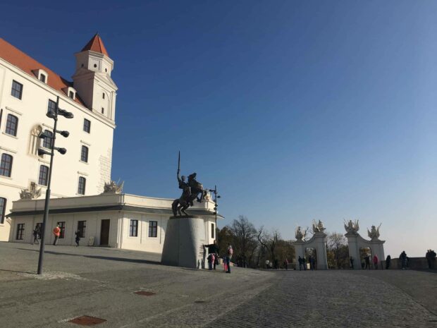 A clear sky above Bratislava with people near the castle and statue, HD Desktop Wallpaper