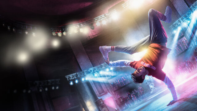 Breakdancing Performer Displays Dynamic Move In Vibrant Arena